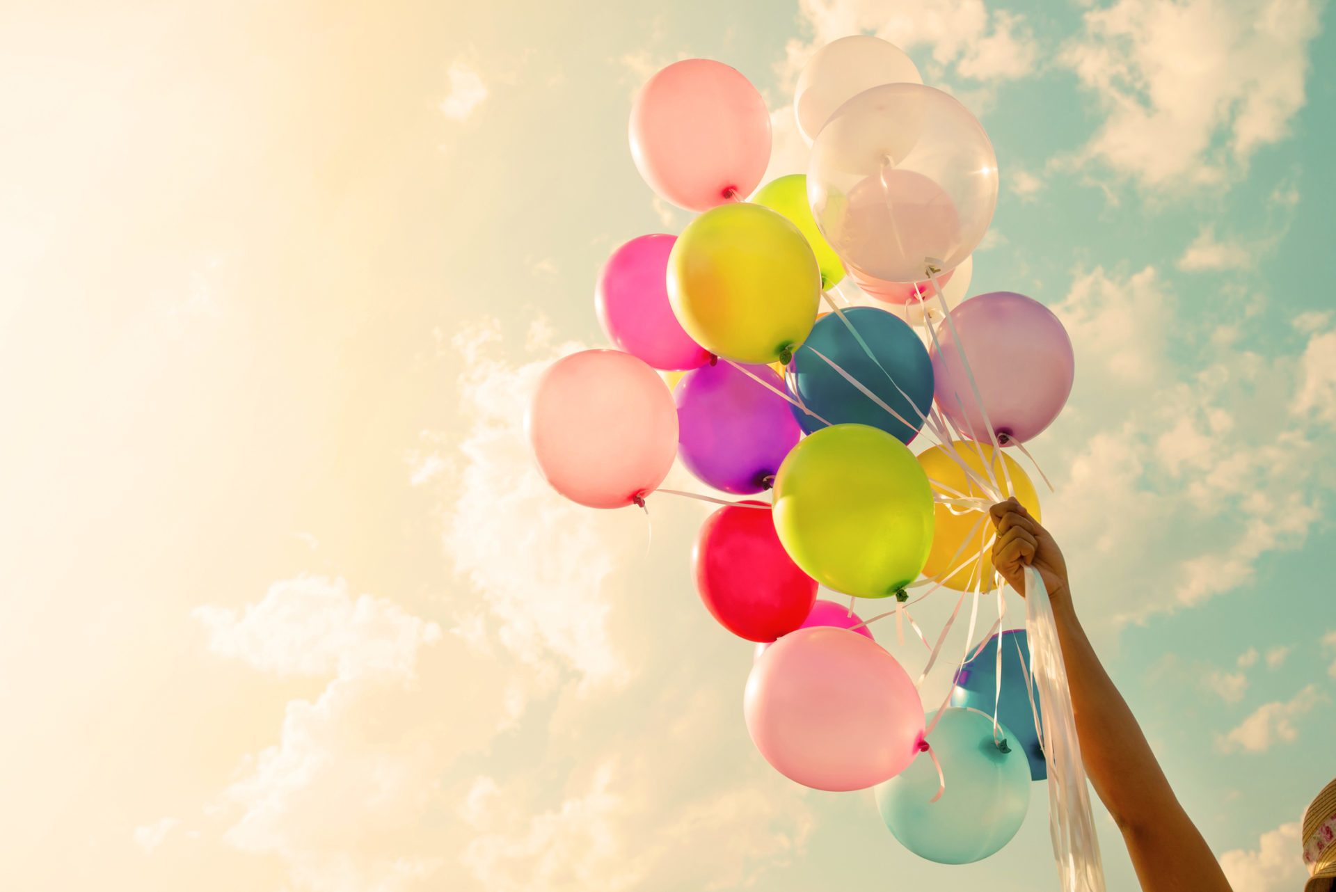 Girl hand holding colorful balloons. happy birthday party. vintage filter effect